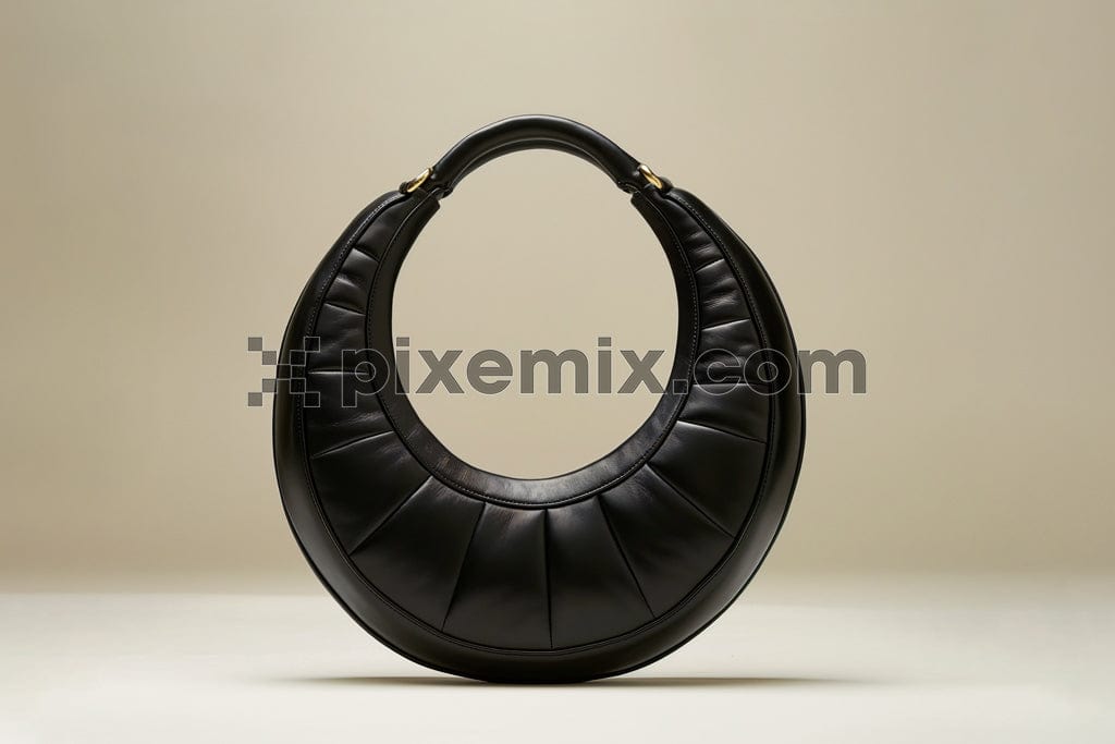 Round black leather bag on beige background image.