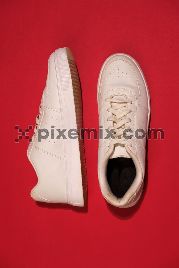 A classic pair of white tennis shoes against a bold red background image.