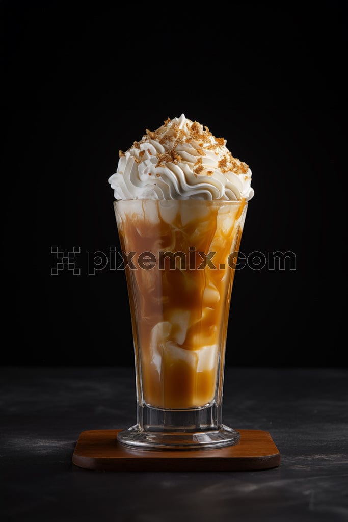 A glass of caramel milkshake topped with whipped cream and caramelised peanuts image.