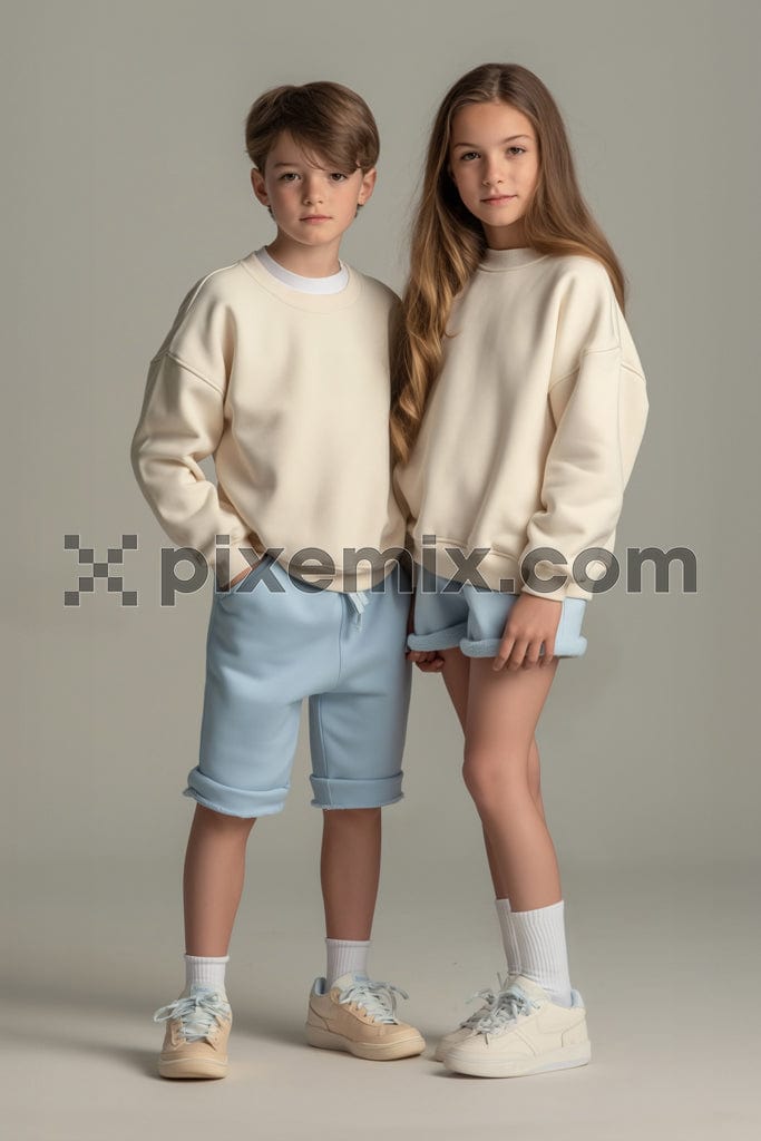 A teenage boy and girl both wearing stylish beige sweatshirts In a professional studio setup image.