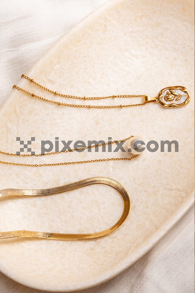  Top view of stylish golden chains and pearl necklaces on plate image.