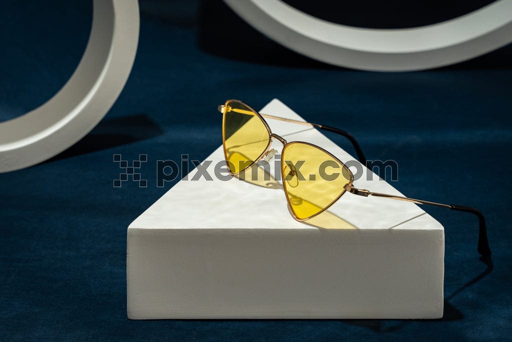 Yellow sunglass on podiums and blue background image.