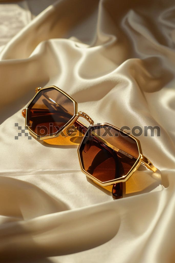 Modern fashionable sunglasses on golden silk image.