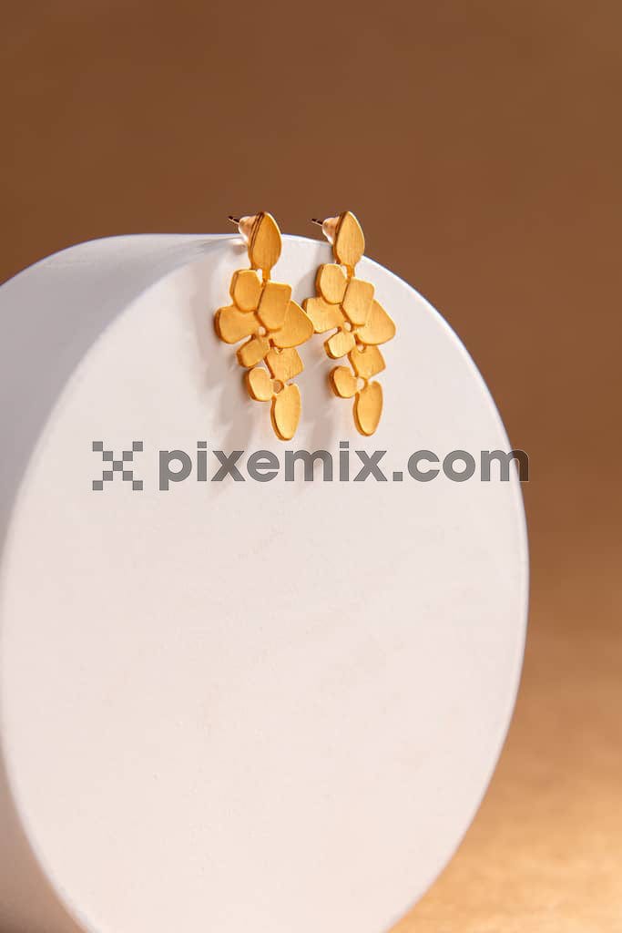 Set of gold earrings Stylish presentation of earrings on white podium image.