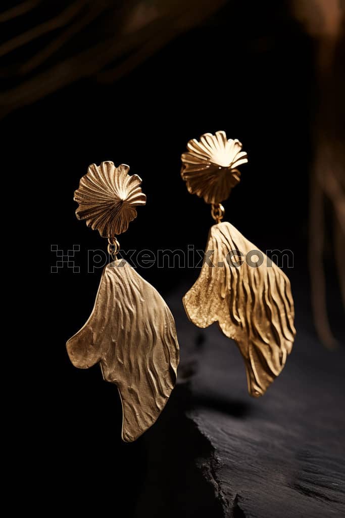 Set of gold earrings on stone image.
