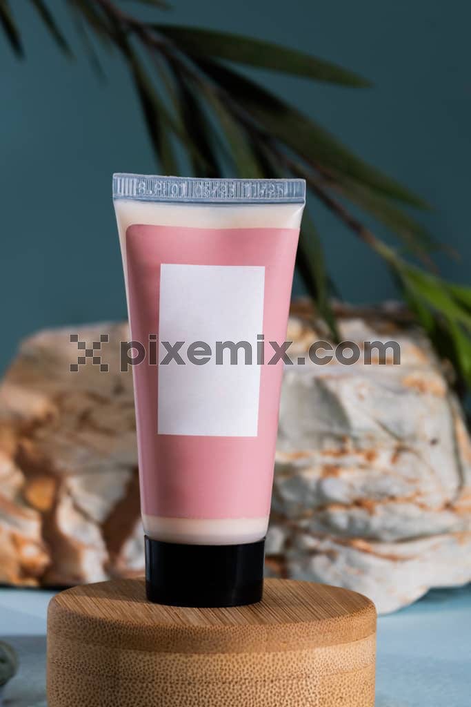 Pink cosmetic tube on blue background image.