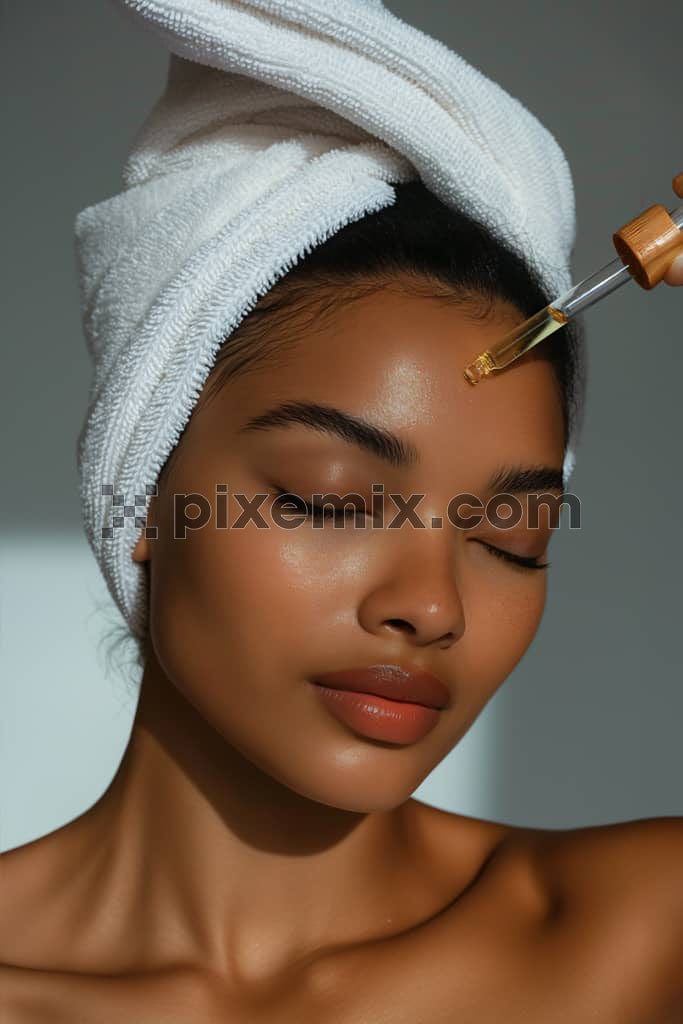 Beautiful young woman applying cosmetic serum on her face image.