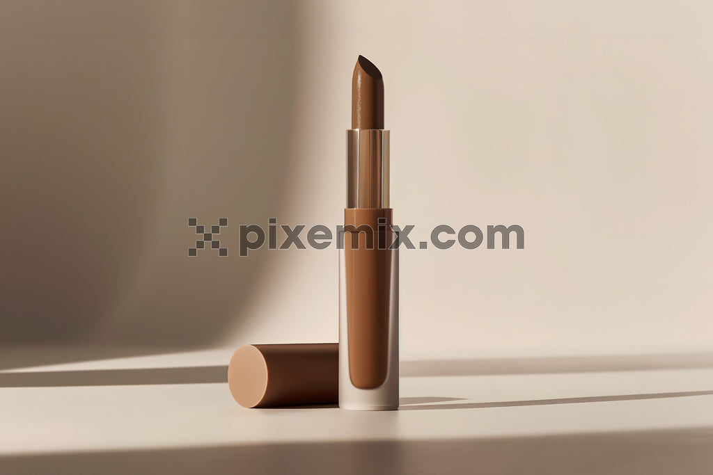 Minimalist beauty shot of nude brown lipstick in elegant packaging with soft shadows on neutral stock image.
