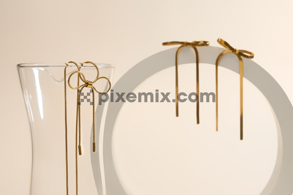 Elegant gold bow earrings displayed on minimal modern props in soft lighting stock image.