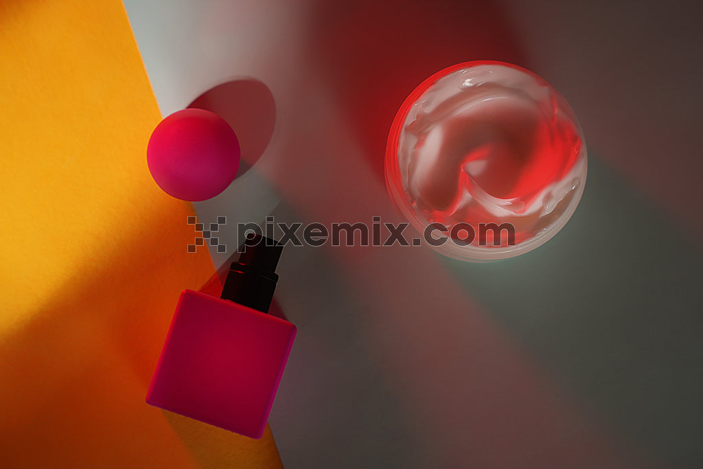 Vibrant skincare flat lay with pink cosmetic containers and moisturizing cream under artistic lighting stock image.