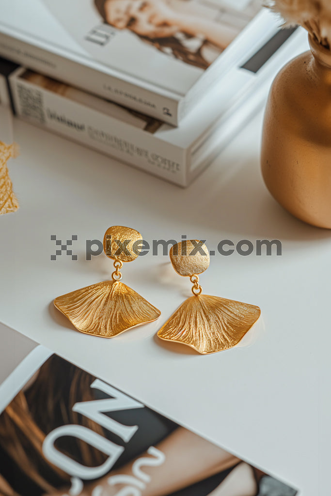 Elegant golden leaf-shaped earrings styled on a fashion magazine with chic, modern decor accents.