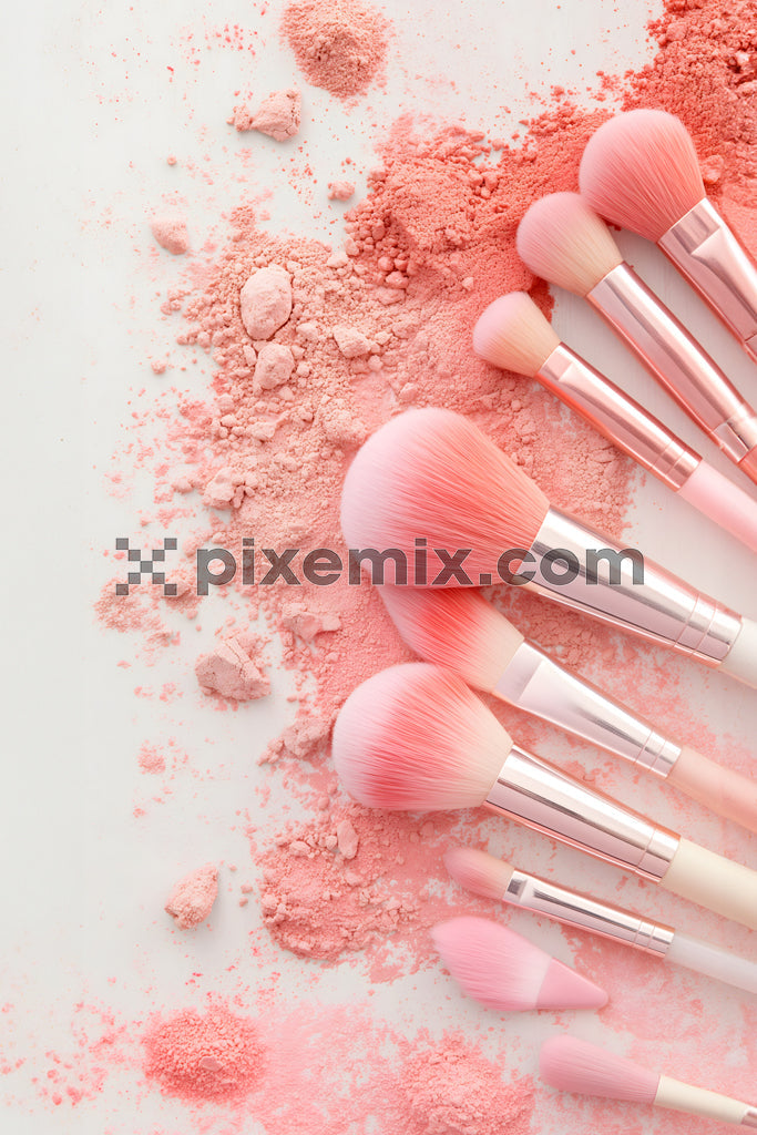 Pink makeup brushes scattered over blush powder in a soft, pastel flat-lay composition stock image.