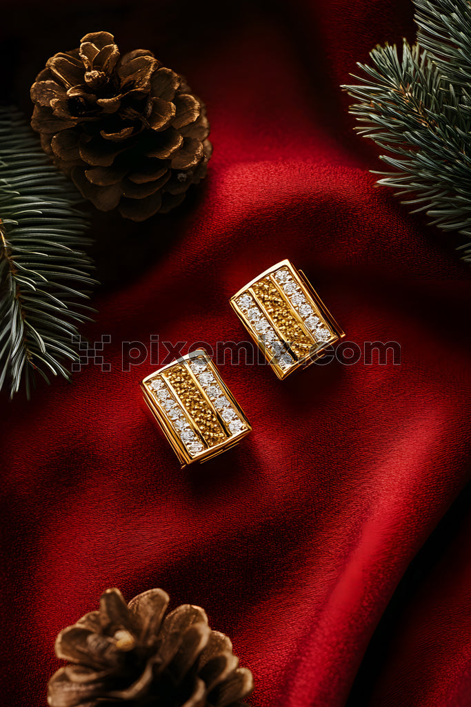 Luxury holiday styling gold and diamond cufflinks on red fabric with pinecones and fir branches stock image.