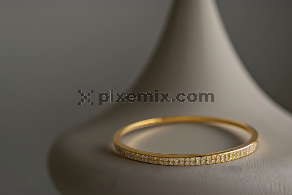 Elegant gold diamond bangle bracelet displayed on sculptural stand with soft luxury lighting.