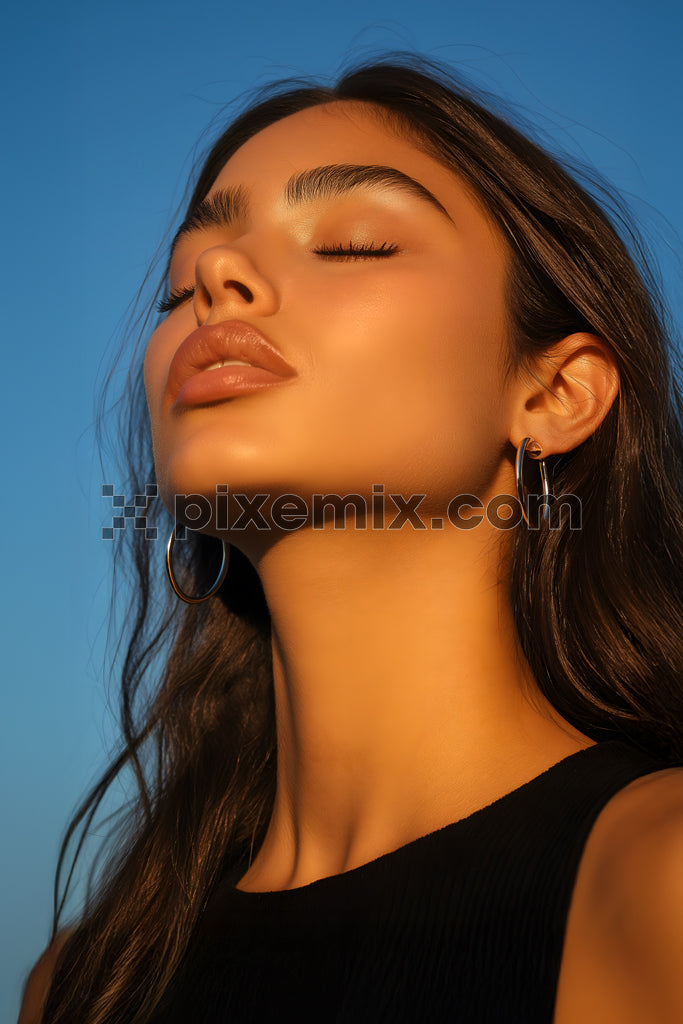 Woman basking in golden sunlight with eyes closed and serene expression stock image.