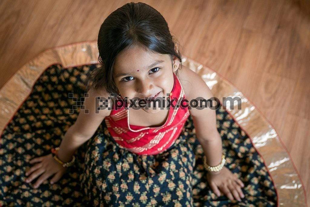 Beautiul Indian cute little girl sitting wearing indian traditional dress image