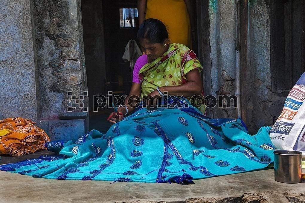 Unidentified women sewing ethnic dresses sell in front of house at village image