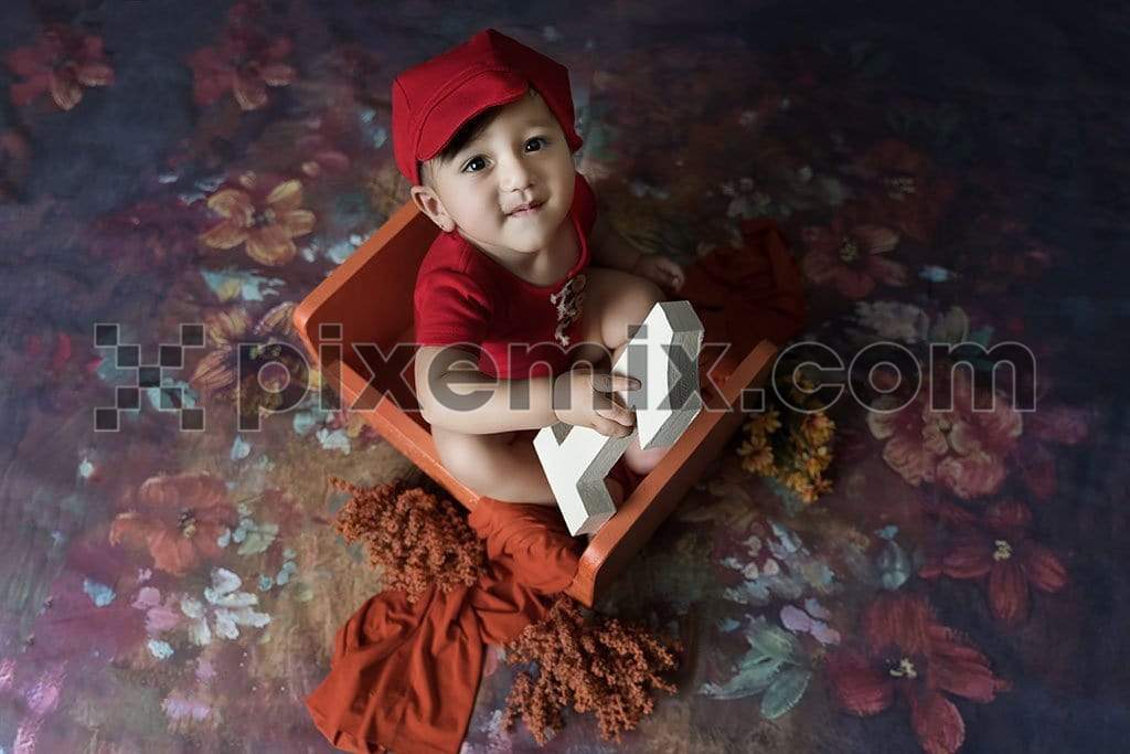Cute baby sitting on floral floor and holding number toy image