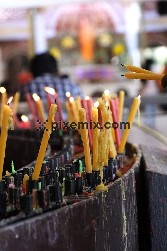 Image of candles lit by people while prayers