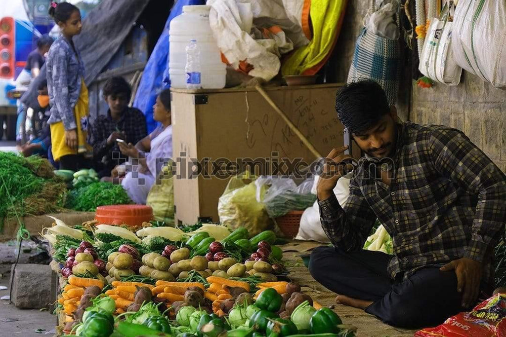 Picture of a vegetable vendor talking on phone in the market