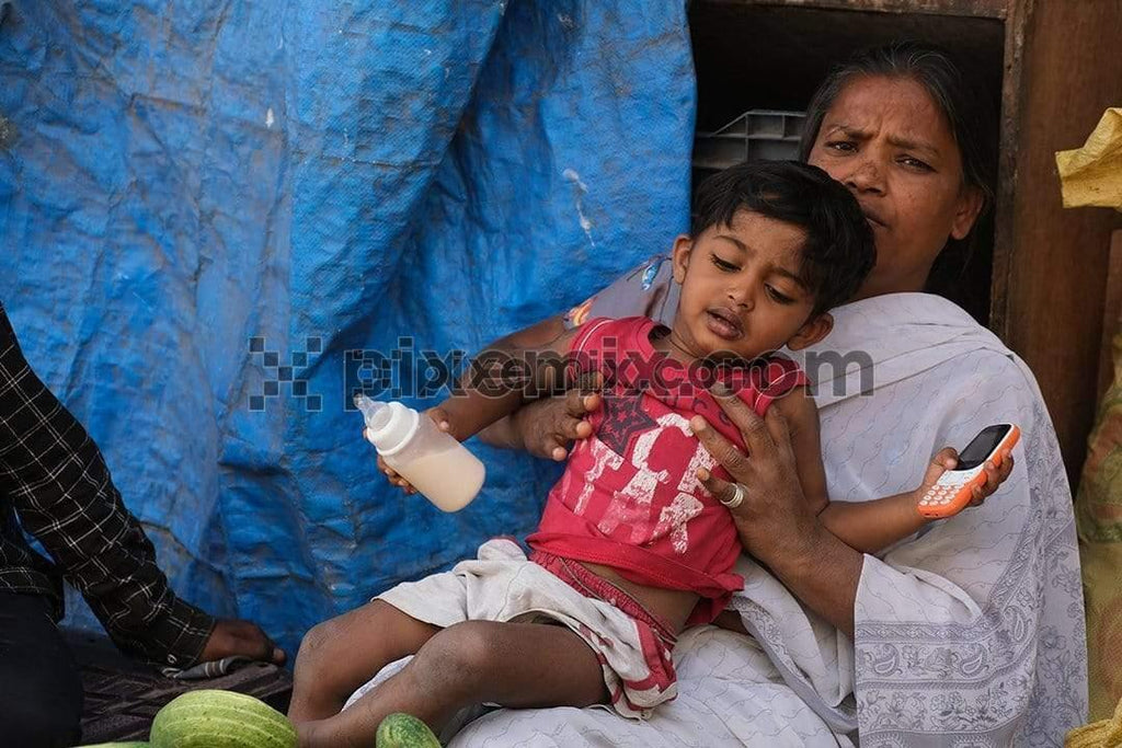 Image of vegetable vendor mother holding her kid to comfort him
