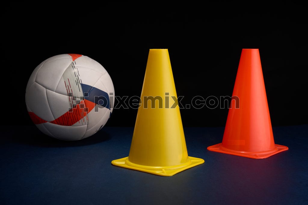 A soccer ball/football rests beside a yellow and an orange traffic cone image.