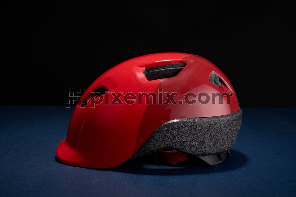 A bright red cycling helmet sits on a blue table image.