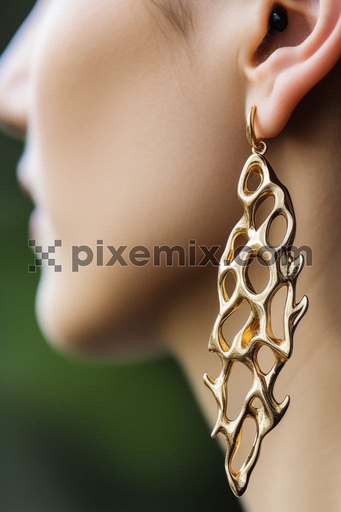 Closeup shot of woman wearing unique shaped gold earrings image.