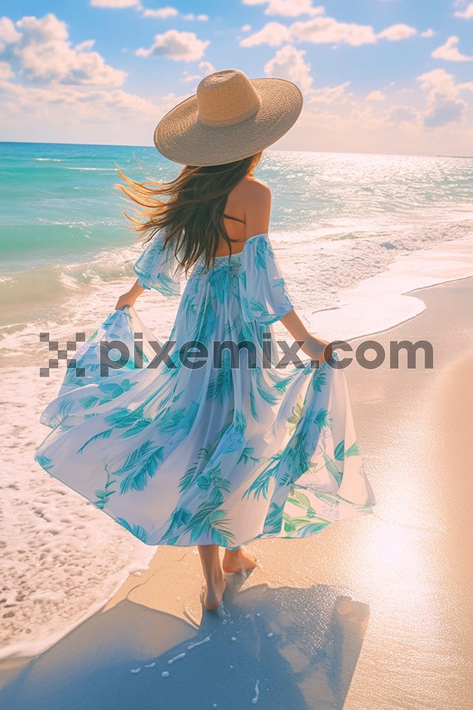 A woman on the beach on a sunny day in a floral blue dress image.